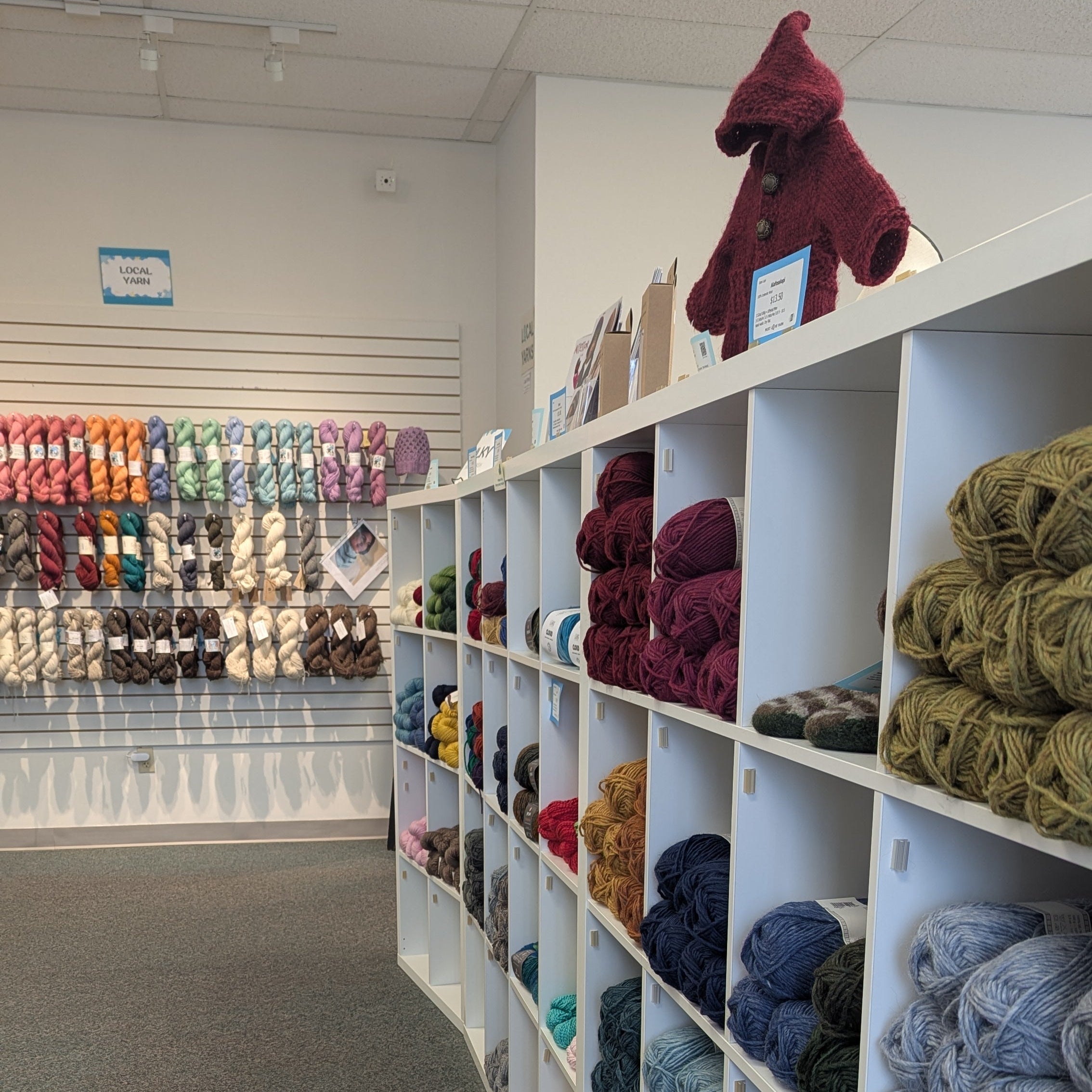 Yarn store with shelves stocked with various colored yarns.
