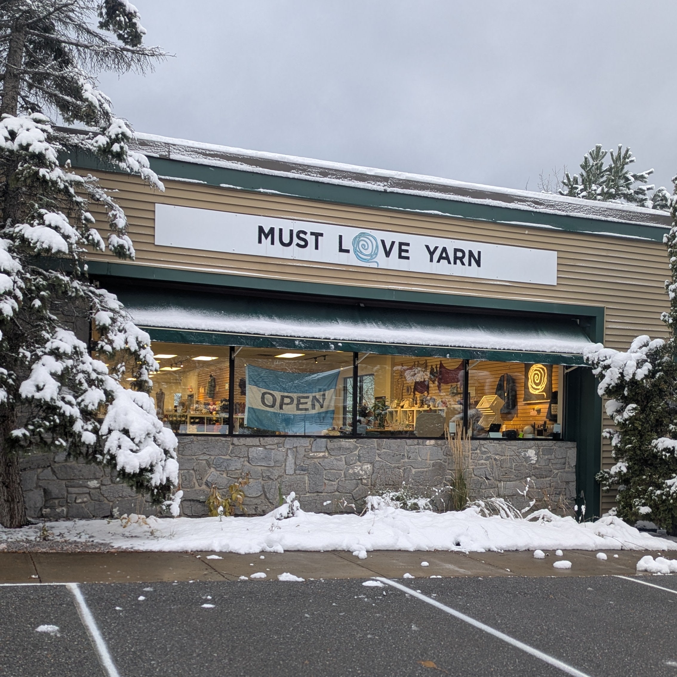 Storefront with 'Must Love Yarn' sign on a snowy day